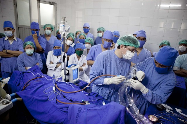 REI Volunteer in surgery with the watching Vietnamese Hospital Staff behind him